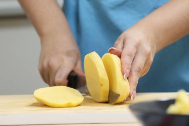 Mutfakta yemek yapan genç bir kadın. Ev hanımı yemek için sebze hazırlıyor. Patates soy. Çorba yapıyorum.