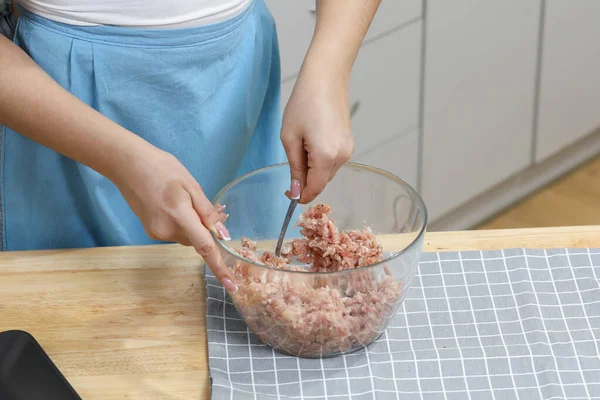 Young woman cooking in kitchen. Housewife preparing vegetables for cooking. Making fresh meat balls . Cooking soup