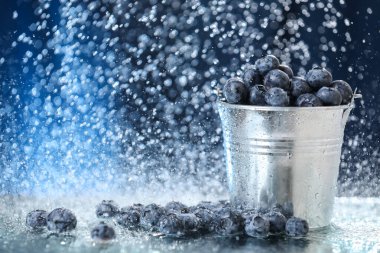 Büyük yaban mersinleri, metal kovanın içinde, suyun altında koyu mavi bir arka planda duruyor. Sağlıklı bir yaşam tarzı. Multivitamin kokteyli. Yaz diyeti. Suyun altında meyve seti. Düşen yaban mersini bahçesi.