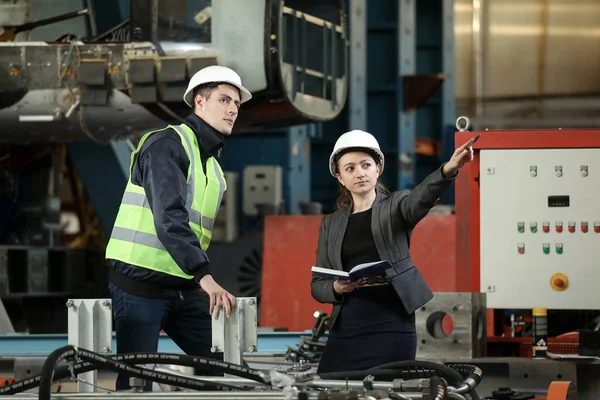 Beyaz bir şapka ve iş elbisesi içinde kadın bir fabrika müdürünün portresi ve iş elbiseli bir fabrika mühendisi. Uçak üreticisinin çalışma sürecini kontrol etmek. 