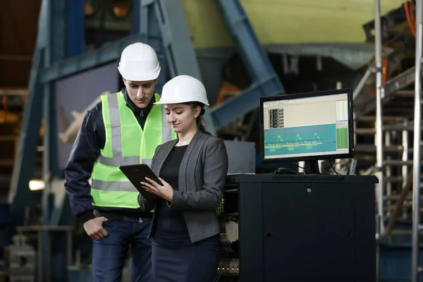 Beyaz bir şapka ve iş elbisesi içinde kadın bir fabrika müdürünün portresi ve iş elbiseli bir fabrika mühendisi. Uçak üreticisinin çalışma sürecini kontrol etmek.