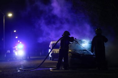 İtfaiyeciler gece yarısı yangına karşı savaşıyor. Polis arabası arkada.. 