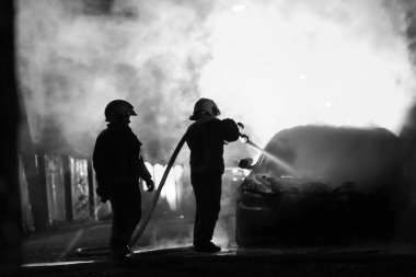 İtfaiyeciler gece yarısı yangına karşı savaşıyor. Polis arabası arkada. Siyah ve beyaz