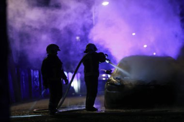 İtfaiyeciler gece yarısı yangına karşı savaşıyor. Polis arabası arkada.. 