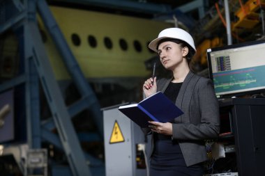 Beyaz kasketli ve takım elbiseli bir fabrika müdürünün portresi. Uçak üreticisinin çalışma sürecini kontrol etmek.