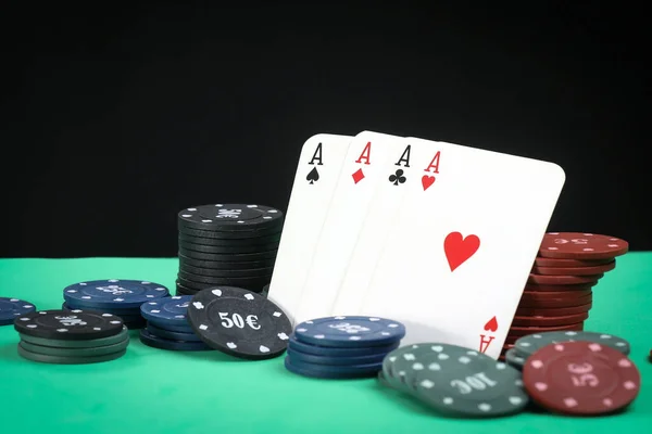 A pair of aces, hearts and diamonds, on a deck of playing cards. Poker playing chips on a green table. Online gambling. Addiction. Falling playing cards and poker chips