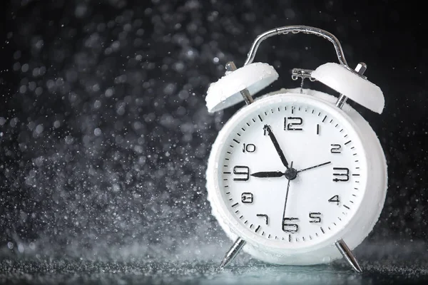 white retro alarm clock in a black background under the water drops.. Morning. Break. Motivation. Business solutions. Success. Deadline.