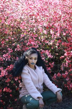 Pembe ağacın yanında oturan kadın