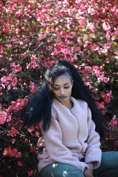 Morena feminina em flores de árvore rosa fundo — Fotografia de Stock