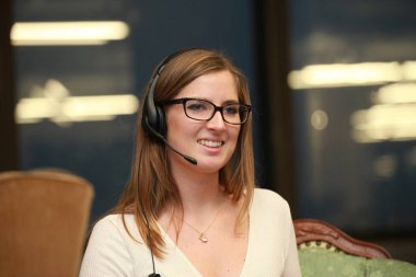 Kulaklıkla konuşurken gülümseyen Yardımcısı