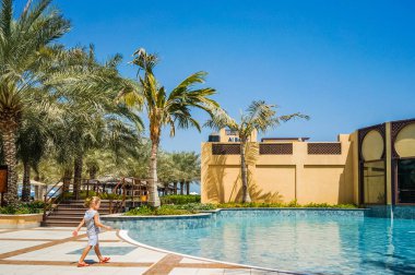 Dubai. 2016 yaz aylarında. Hilton Ras Al Khaima otel Basra Körfezi üzerinde vaha. Küçük bir çocuk havuza gidiyor. 