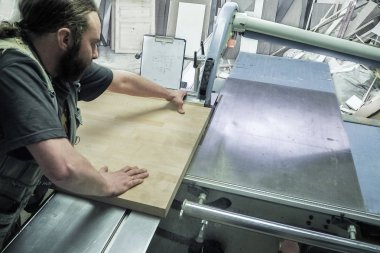 Mobilya fabrikası için testere testeresi kesen bir işçi. Dairesel testere. Marangoz işyeri manzarası. - Rusya. Saint-Petersburg 'da. Haziran 2017