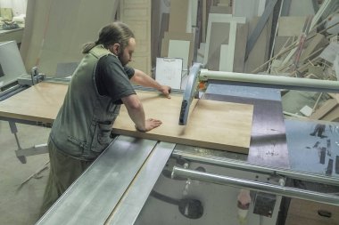 Mobilya fabrikası için testere testeresi kesen bir işçi. Dairesel testere. Marangoz işyeri manzarası. - Rusya. Saint-Petersburg 'da. Haziran 2017