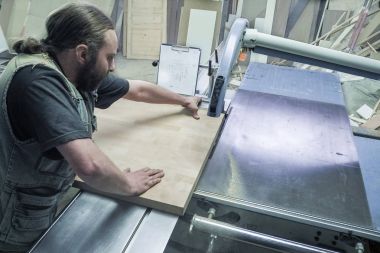 Mobilya fabrikası için testere testeresi kesen bir işçi. Dairesel testere. Marangoz işyeri manzarası. - Rusya. Saint-Petersburg 'da. Haziran 2017