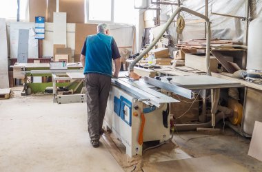 Mobilya fabrikası için testere testeresi kesen bir işçi. Dairesel testere.