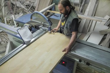 Mobilya fabrikası için testere testeresi kesen bir işçi. Dairesel testere. Marangoz işyeri manzarası. - Rusya. Saint-Petersburg 'da. Haziran 2017