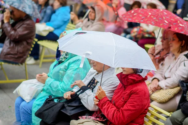 İnsan yağmurlu bir günde şemsiye altında bir konser dinlemek. Saint-Petersburg. 2016 yaz.