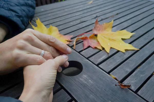 Manos juntas. Una mano de ayuda a un amigo en el fondo de otoño mesa áspera con hojas de arce . — Foto de Stock