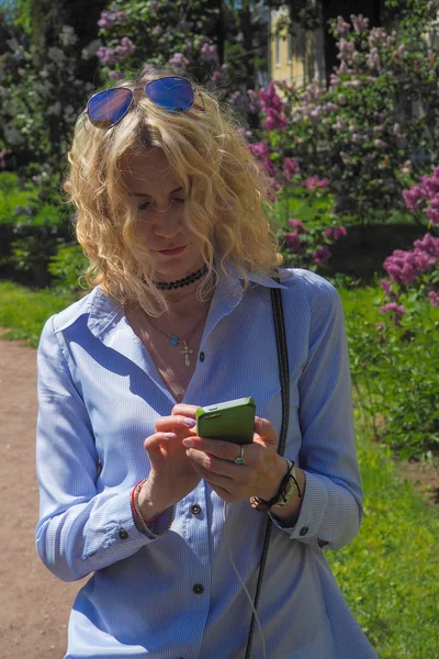 Mulher de negócios em terno cinza-azul usando um dispositivo móvel no Parque — Fotografia de Stock