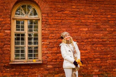 Bayan Beyaz giysili sonbahar vintage kırmızı tuğla duvar kemerli pencere ile bir arka plan üzerinde poz.