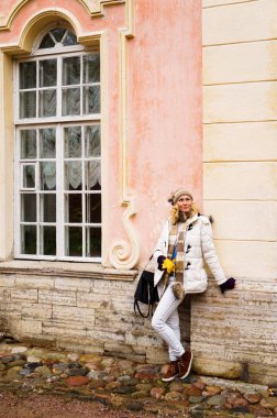 Bayan pembe duvar kemerli pencere ile bir arka plan üzerinde poz Beyaz giysili.