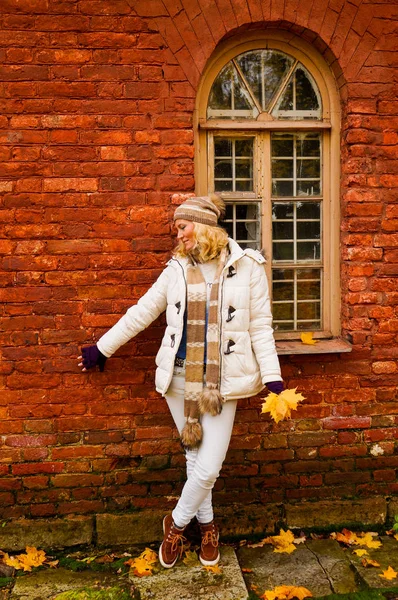 Bayan Beyaz giysili sonbahar vintage kırmızı tuğla duvar kemerli pencere ile bir arka plan üzerinde poz.