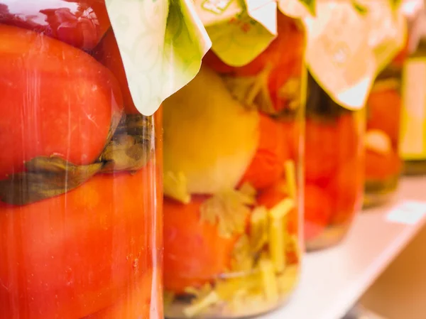 Latas enlatadas de tomates y verduras se colocan en una fila sobre un fondo claro y borroso . — Foto de Stock