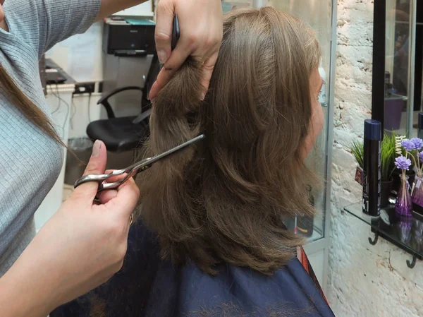 Peluquería de cerca cortar el pelo de una mujer en el salón de peluquería . — Foto de Stock