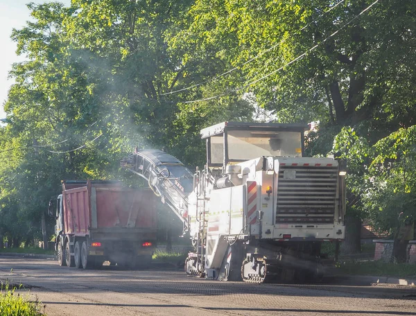 La carretera funciona en la ciudad. Trabajar en equipos especiales cortó el asfalto viejo en un día soleado de verano. —  Fotos de Stock
