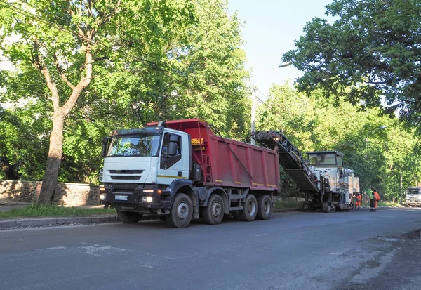 La carretera funciona en la ciudad. Trabajar en equipos especiales cortó el asfalto viejo en un día soleado de verano. —  Fotos de Stock