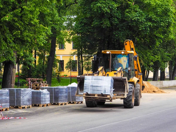 El tractor transporta las unidades de embalaje. El camino funciona. La mejora de la ciudad . —  Fotos de Stock