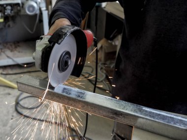 Daire testere ile kesme kıvılcım. Elektrik değirmeni aracıyla fabrikasında, çelik yapı üzerinde çalışan bir erkeğin kıvılcım uçan. 