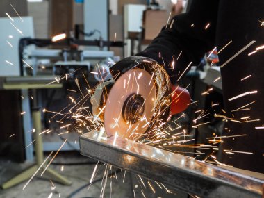 Daire testere ile kesme kıvılcım. Elektrik değirmeni aracıyla fabrikasında, çelik yapı üzerinde çalışan bir erkeğin kıvılcım uçan. 