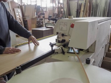 Kenar bantlama makinesi. Kenar bantlama makineleri için plastik bandı kaplama mobilya bobinleri. Bir işçi bir kenar üstünde belgili tanımlık makine yapıştırır..