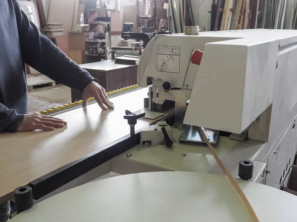 Bagueuse de bord. Bobines de meubles bords de finition bande en plastique pour les machines à baguer. Un travailleur colle un bord sur la machine . — Photo