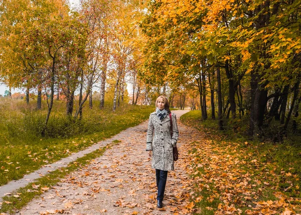 Blond kobieta w średnim wieku jesienią na tle przyrody. — Zdjęcie stockowe