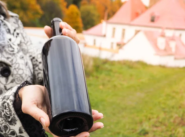 Bottiglia di vino rosso in mani femminili sullo sfondo di un antico castello . — Foto Stock