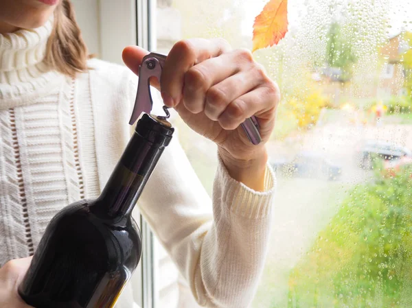 El sacacorchos abre una botella de vino sobre un fondo brillante festivo . — Foto de Stock