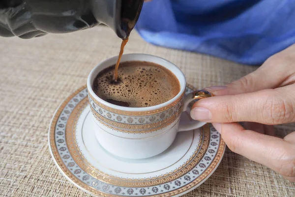Hand hält eine Tasse Kaffee. schwarzer Kaffee aus der Türkei gegossen. — Stockfoto
