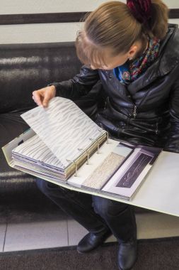 Kumaş perdeler için katalog alıcı kadın bakar.
