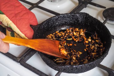 Bir tavada pişmiş soğan. Kötü bir mutfak. Zararlı gıda ve kanserojen kavramı.