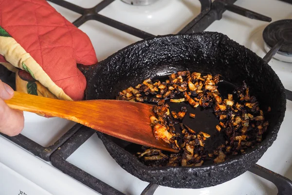 Overcooked onion in a pan. A bad kitchen. The concept of harmful food and carcinogens.