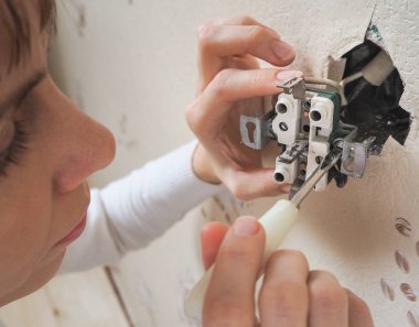Kadın elektrikçi onarım duvar prizine.