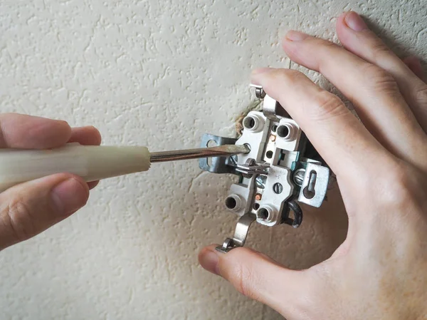 Electrician repair the outlet on the wall.