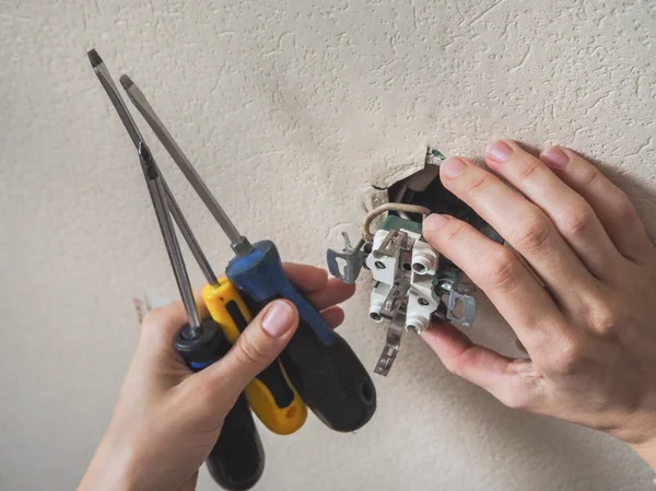 Electrician repair the outlet on the wall.