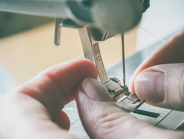 Sewing process close-up on the sewing machine. The presser foot and needle of the sewing machine during operation.