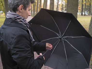 Adam parkta siyah şemsiye ile.