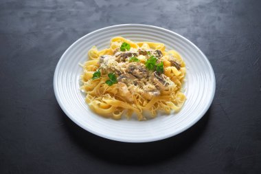 Gri bir arka plan üzerine mantarlı makarna. Metniniz için kopya alanı.