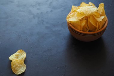 Lezzetli patates cipsi karanlık bir arka plan üzerinde tutan kadınların elleri.