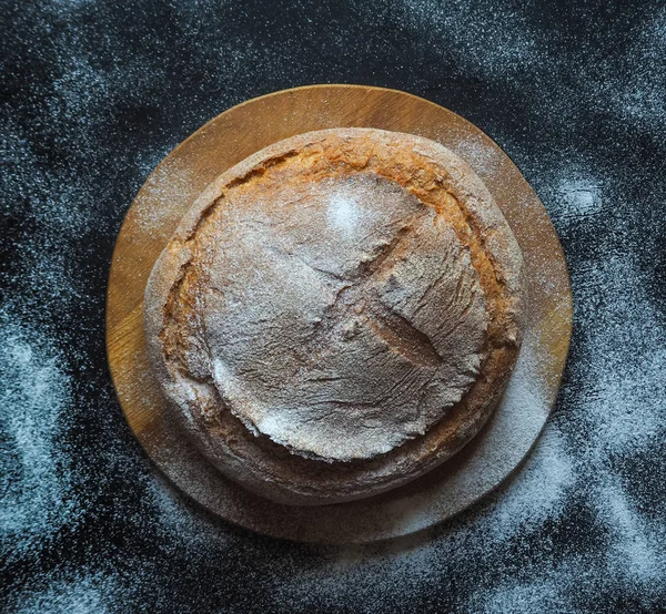 Круглий запечений хліб на чорному столі. Вид зверху . — стокове фото